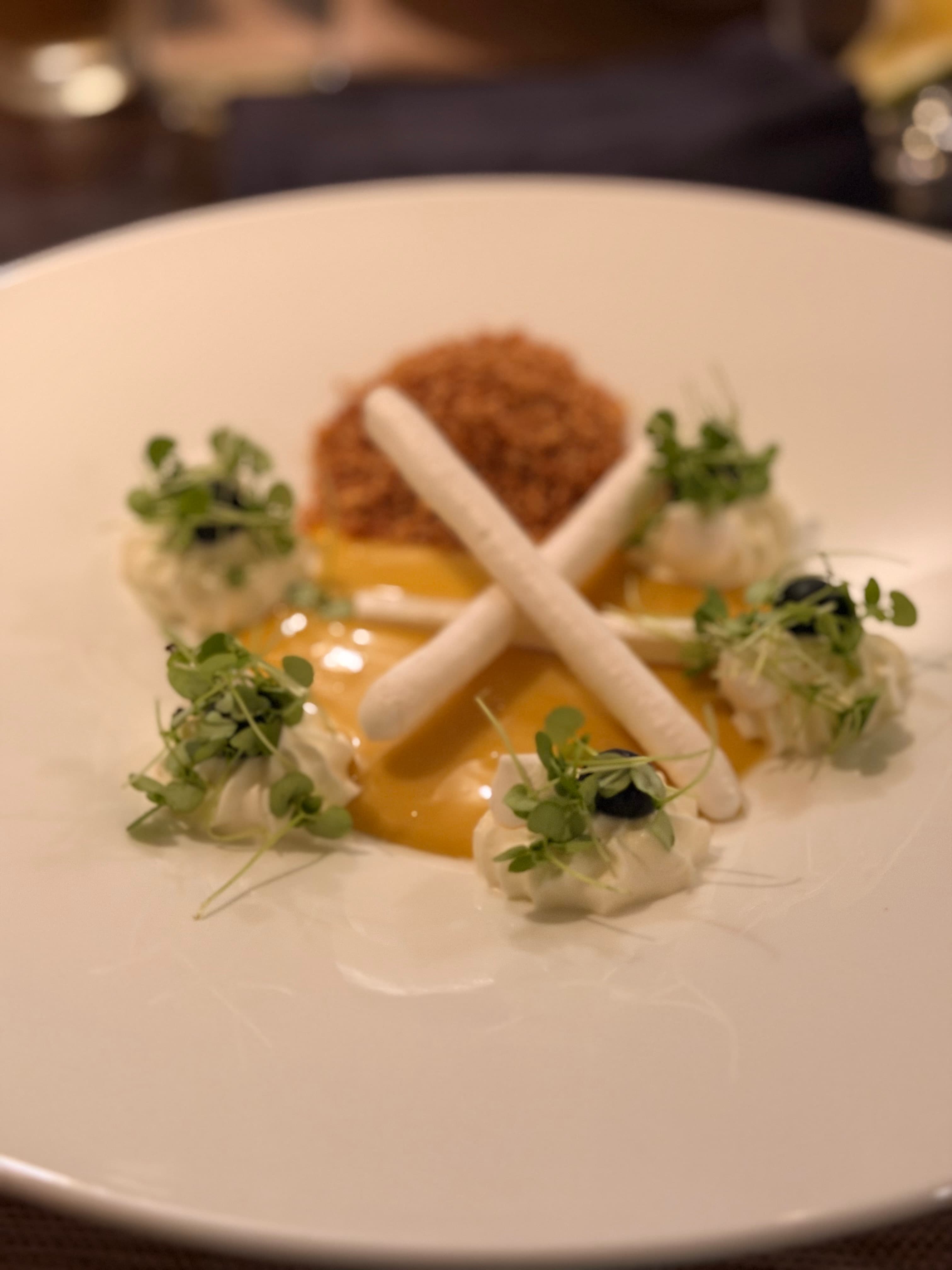 Deconstructed passion-fruit dessert with crossed pavlova pieces, cream, blueberries and crumble